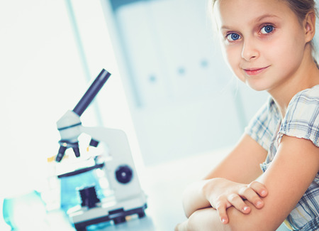 Schoolgirl looking through microscope in science classの写真素材