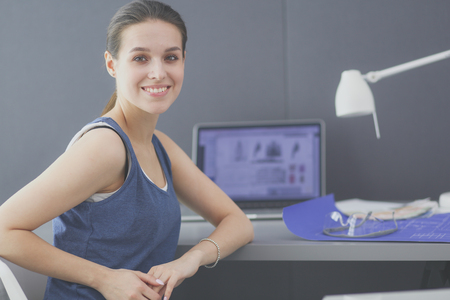 Young woman sitting at the desk with instruments, plan and laptop.の写真素材