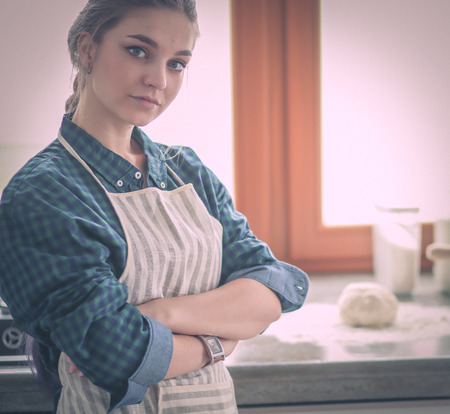 Young woman standing by the stove in the kitchen .の写真素材