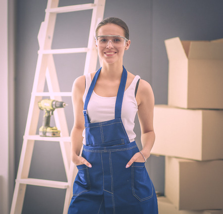 Happy beautiful young woman doing wall painting, standing near ladderの写真素材