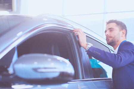 Dealer stands near a new car in the showroomの写真素材