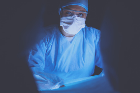 Doctors team in surgery in a dark background.の写真素材