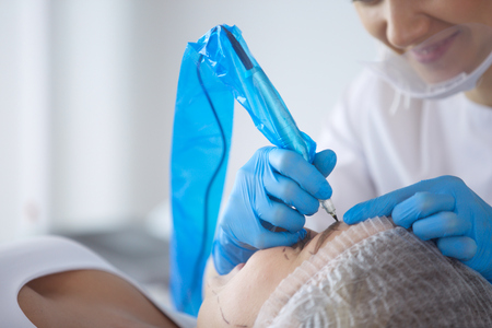 Permanent makeup for eyebrows. Closeup of beautiful woman with thick brows in beauty salon.の写真素材