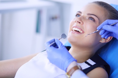 Young Female patient with open mouth examining dental inspection at dentist office.の写真素材