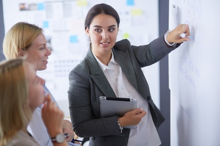 Business, education and office concept - business team with flip board in office discussing something.の写真素材