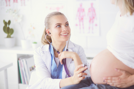 Smiling woman doctor shows pictures on the tablet to pregnant young woman at hospital.の写真素材