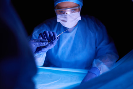 Doctor performing surgery in a dark background.