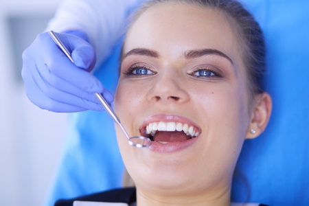 Young Female patient with open mouth examining dental inspection at dentist office.の写真素材
