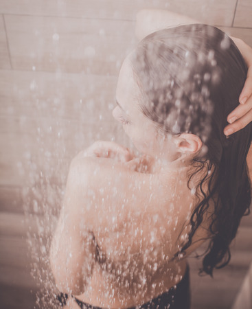 Young beautiful woman under shower in bathroom.の写真素材