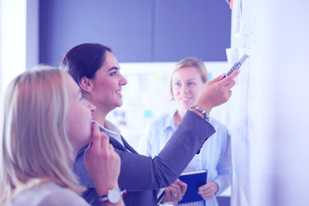 Business, education and office concept - business team with flip board in office discussing something.の写真素材