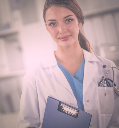 Portrait of young woman doctor with white coat standing in hospitalの写真素材