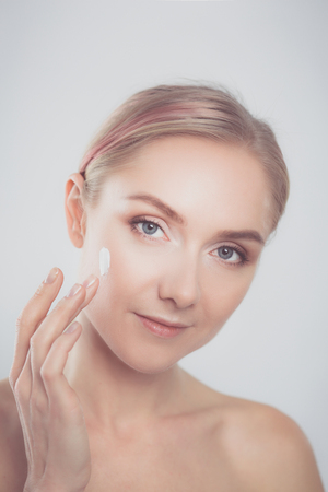 The beautiful young girl with a clean fresh skin touches with her cheekの写真素材
