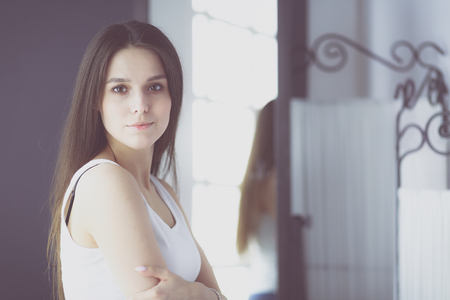 Young woman with reflection in mirror at home.の写真素材