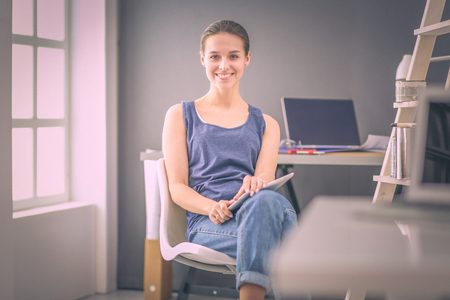 Young woman sitting at the desk with instruments, plan and laptop.の写真素材