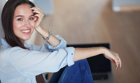 Young beautiful woman at home sitting on the floor with laptop.の写真素材