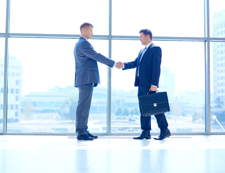 Full length image of two successful business men shaking hands with each otherの写真素材