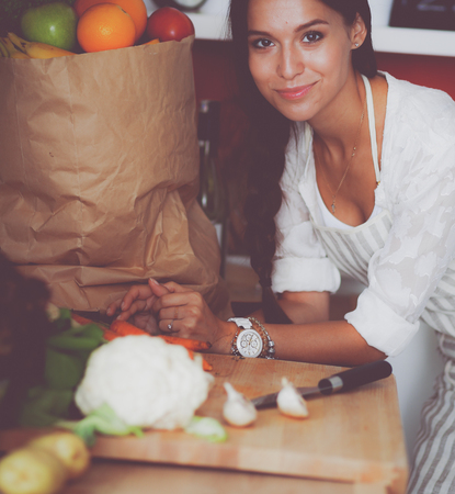 Young woman standing near desk in the kitchen. Young woman .の写真素材