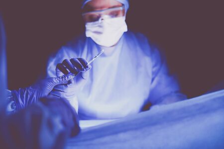 Doctor performing surgery in a dark background.の写真素材