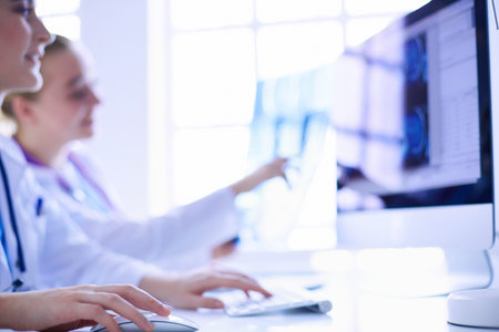 Female doctors looking and discussing x-ray image at hospital.