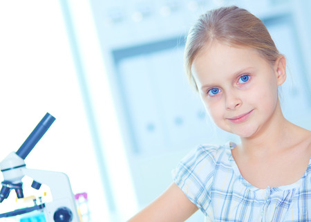 Schoolgirl looking through microscope in science class.の写真素材