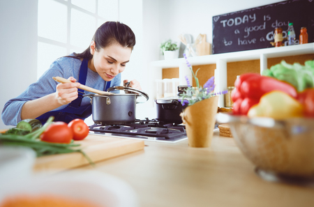 Cooking woman in kitchen with wooden spoonの写真素材