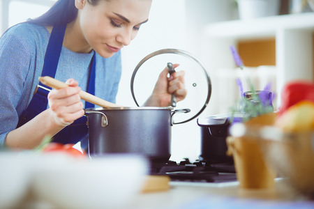 Cooking woman in kitchen with wooden spoonの写真素材