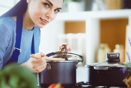 Cooking woman in kitchen with wooden spoonの写真素材