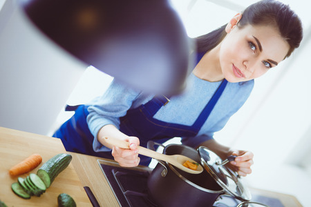 Cooking woman in kitchen with wooden spoonの写真素材
