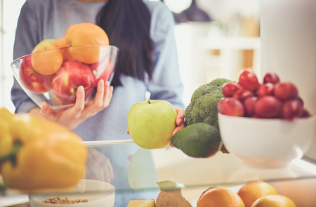 Smiling woman taking a fresh fruit out of the fridge, healthy food conceptの写真素材