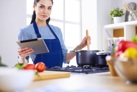 Young woman using a tablet computer to cook in her kitchenの写真素材