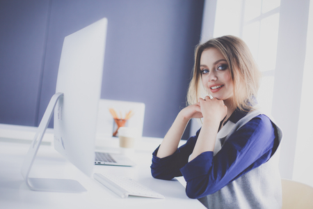 Young confident businesswoman working at office desk and typing with a laptopの写真素材