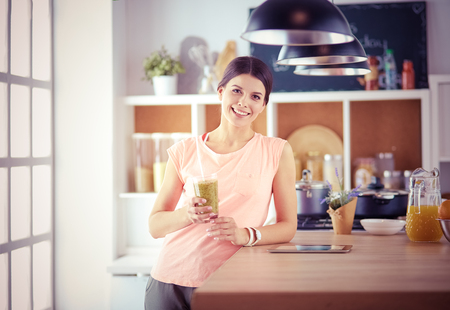 Beautiful young woman using a digital tablet in the kitchen.の写真素材