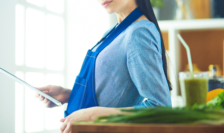 Young woman using a tablet computer to cook in her kitchenの写真素材