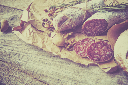 Italian salami wih sea salt, rosemary, garlic and nuts on paper. Rustic style. Close up.の写真素材