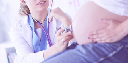 Smiling woman doctor shows pictures on the tablet to pregnant young woman at hospital.の写真素材