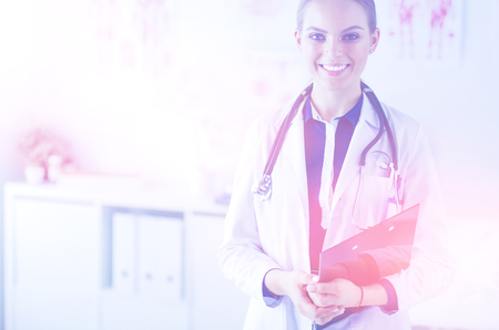 Smiling female doctor with a folder in uniform standingの写真素材
