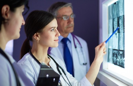 Group of doctors examining x-rays in a clinic, thinking of a diagnosisの写真素材