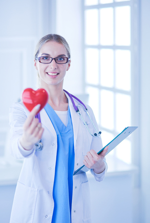 Female doctor with the stethoscope holding heartの写真素材