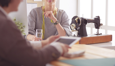 Female dressmaker is communicating with the potential client about custom-made dress in the sewing workshopの写真素材