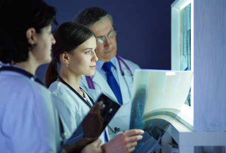 Group of doctors examining x-rays in a clinic, thinking of a diagnosisの写真素材