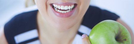 Close up portrait of healthy smiling woman with green apple.の写真素材