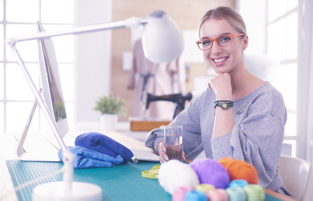 Beautiful fashion designer sitting at the desk in studioの写真素材