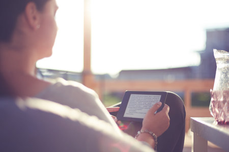 Smiling young woman sitting on sofa with touchpad.