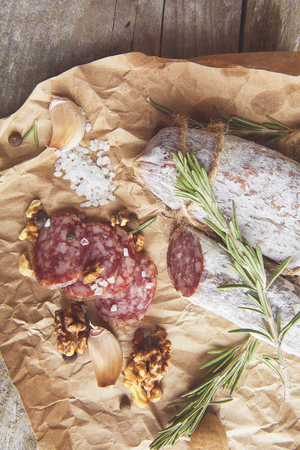 French salami and walnuts on craft paper on wooden backgroundの写真素材