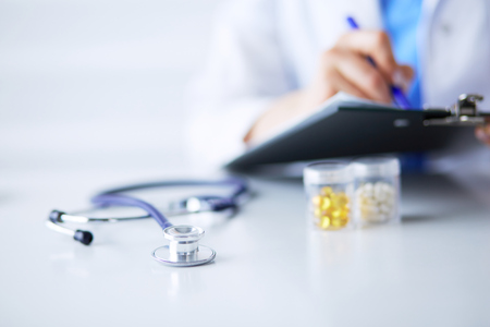 Stethoscope lying on glass desk with laptop computer at busy physician background. Medicine or pharmacy concept. Medical tools at doctor working tableの写真素材