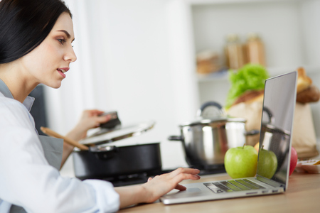 Young woman using a tablet computer to cook in her kitchen.の写真素材