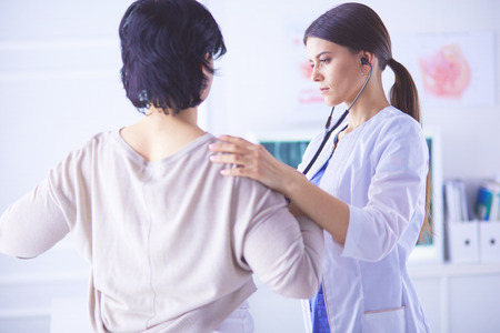 A female doctor listening a patient with a stethoscopeの写真素材