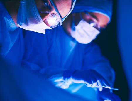 Doctors team in surgery in a dark background.の写真素材