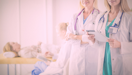 Portrait of two confident female doctors standing with arms crossed at the medical office.の写真素材