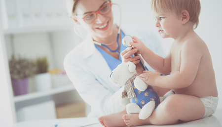 Female doctor is listening kid with a stethoscope in clinicの写真素材